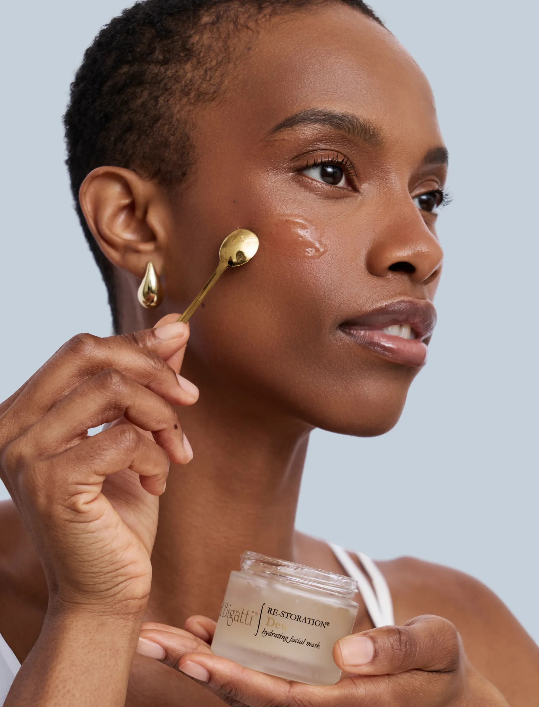 African American woman applying Dew moisturizer on her face